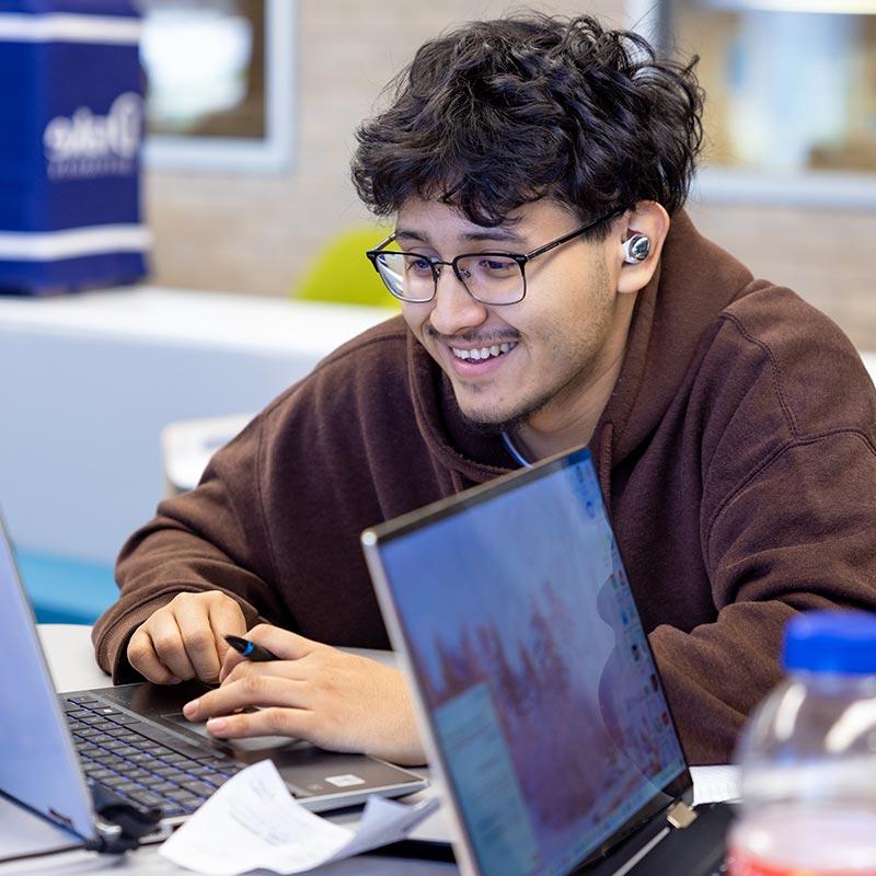 Student smiling while looking at a laptop.